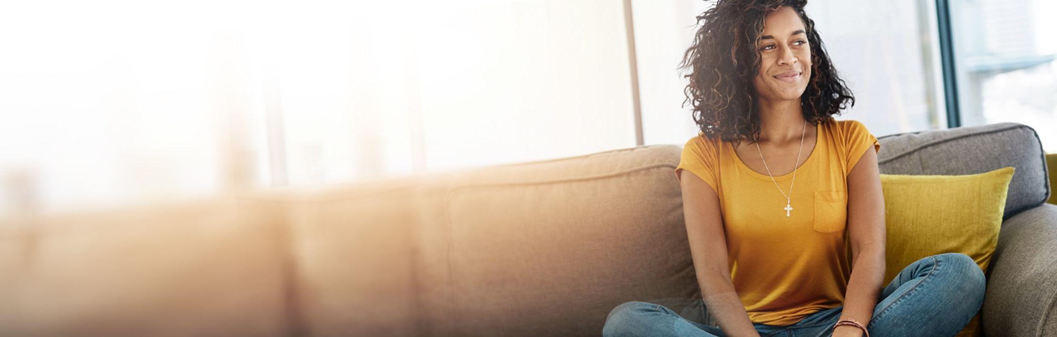 A woman enjoys the sunlight streaming through her windows at home.